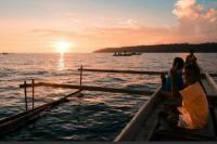 Salah seorang nelayan sementara menangkap ikan dengan memancing di laut.